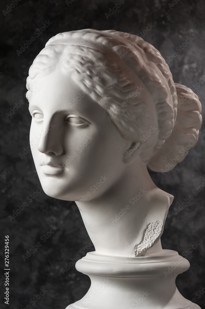 Gypsum copy of ancient statue Venus head on a dark textured background. Plaster sculpture woman face. Gypsum copy of ancient statue Venus head on a dark textured background. Plaster sculpture woman face.