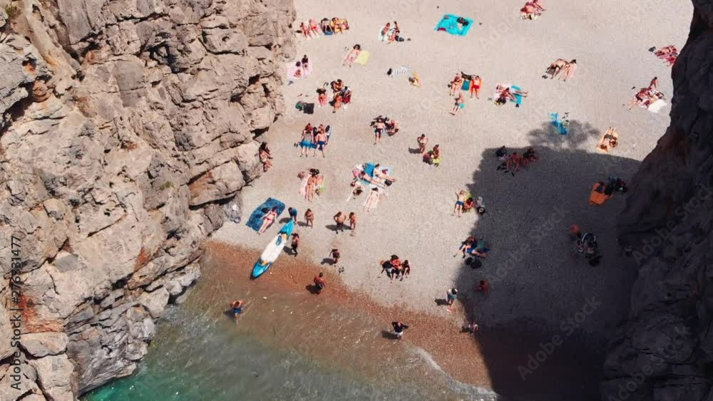 Aerial fly over view of Torrent de Pareis - canyon with beautiful beach on Mallorca, Spain. People relaxing on the beach.