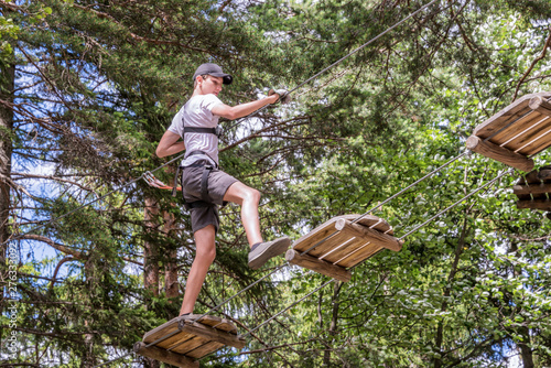 Photography Teenager having fun on high ropes course, adventure, park, climbing trees in a f