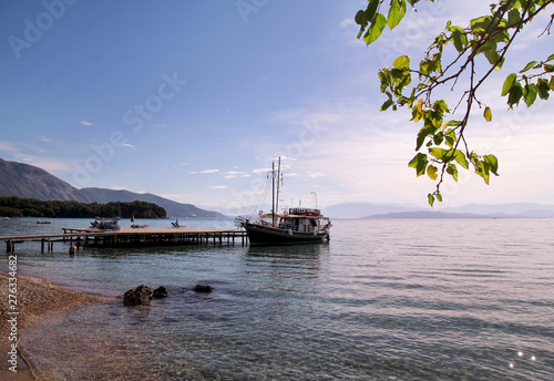 Tourist boat cruiser in small marina on sea and beautiful beach, waiting tourists for ship is sailing out of port for next tourist tour. Anchored cruise ship in harbor. Summer season, travel, holiday.