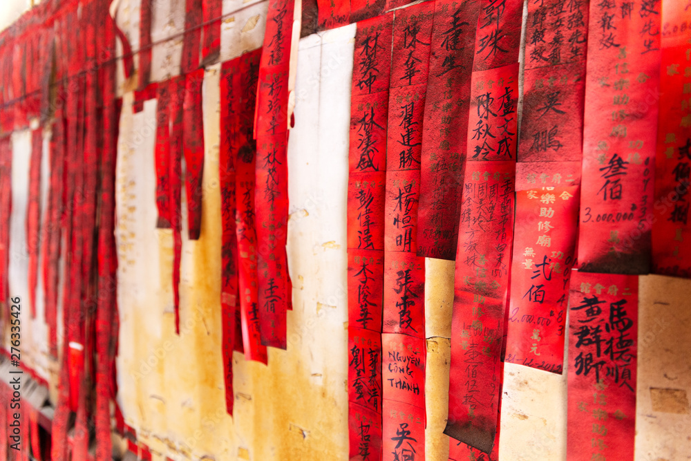 Red paper prayer flags or prayer slips with names in Chinese black ink