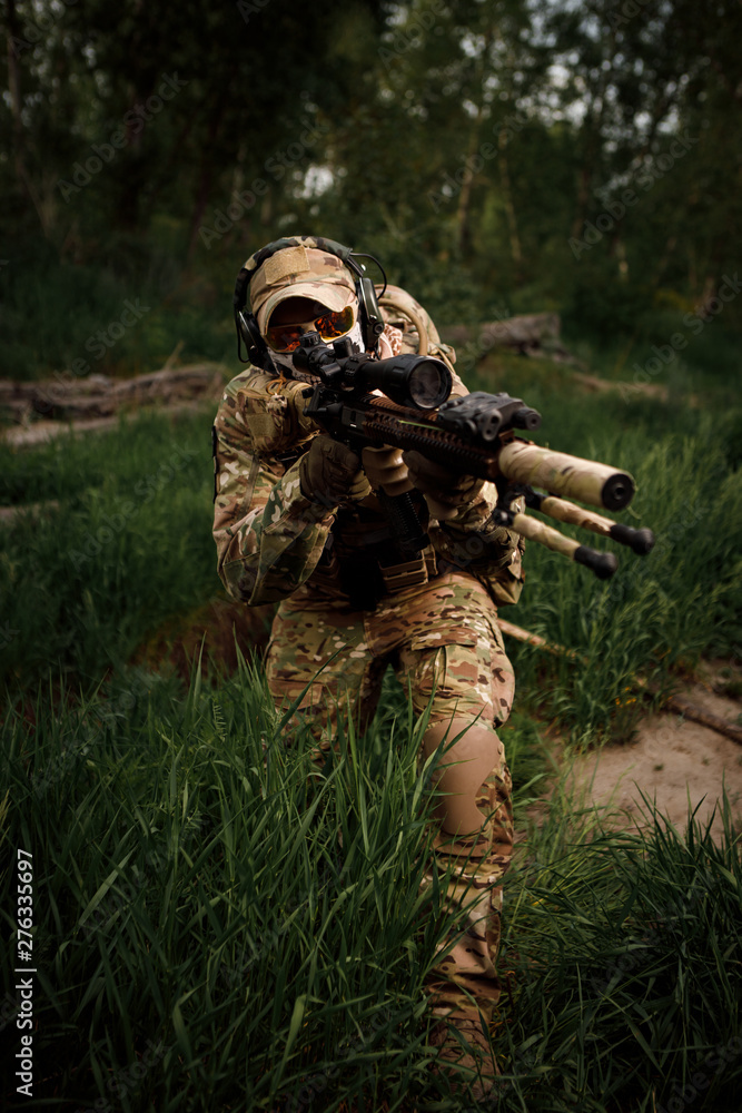 Portrait airsoft soldier with a rifle playing strikeball in outdoor in grass