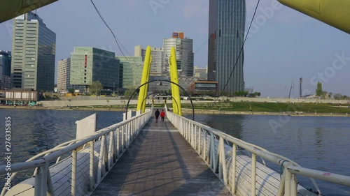 Vienna, Austria - April 08 2019: Beginning of summer in Austria. View from Ponte Cagrana. People passing, New Danube and office buildings visible in the background. photo