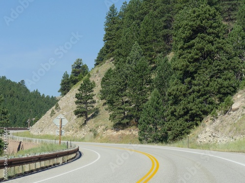 Scenic winding road along cliffs and mountains with protective rail fence at Bighorn National Forest in northern Wyoming. photo