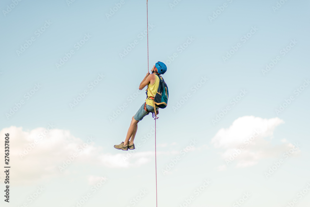 Happy successful rock climber hanging on rope