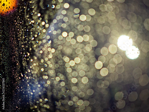 Rain drops texture on car window with colorful bokeh abstract background.