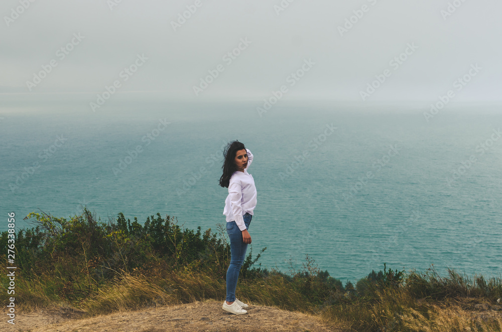 young casual woman travel  in white t shirt and jeans   posing near sea