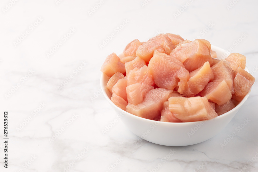 Raw chicken small pieces close up on marble background Raw chicken small pieces close up on marble background