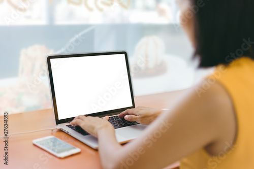 Mock up image of a woman using laptop with blank white screen in cafe. Cropped shot women using laptop with a coffee cup on table.