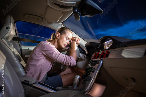 Fotografia Young female driver at the wheel of her car, super tired, falling asleep while d