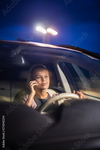 фотографія Young female driver playing with her cellphone instead of paying attention to dr