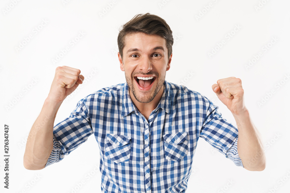 Photo of unshaved delighted man in casual shirt wondering and smiling at camera with clenched fists Photo of unshaved delighted man in casual shirt wondering and smiling at camera with clenched fists