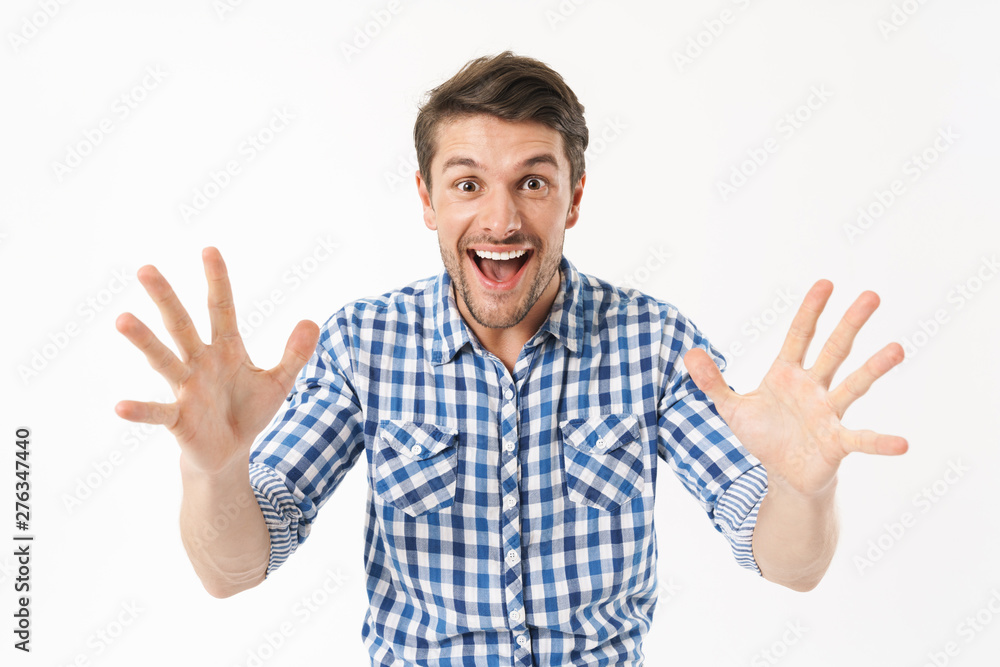 Photo of happy delighted man in casual shirt wondering and smiling at camera with throwing up arms Photo of happy delighted man in casual shirt wondering and smiling at camera with throwing up arms