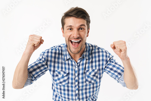Photo of unshaved delighted man in casual shirt wondering and smiling at camera with clenched fists