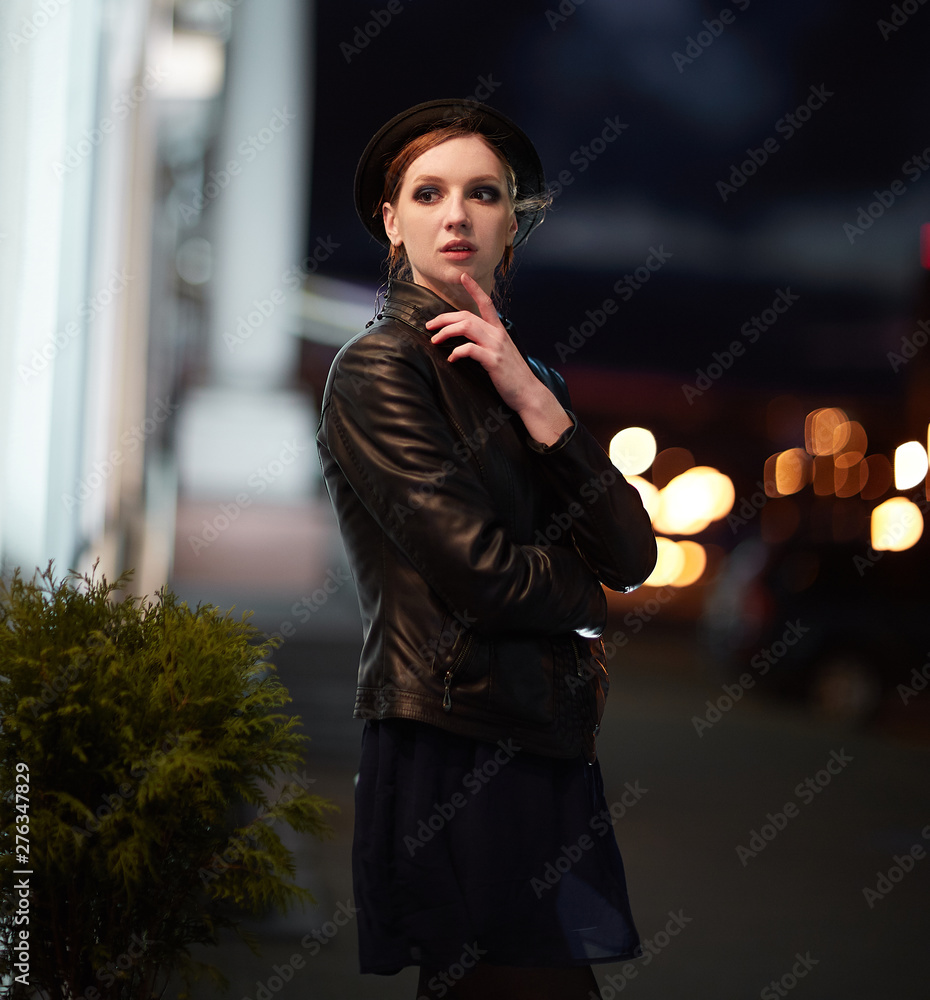 brooding young woman looking at the lights in the night city.
