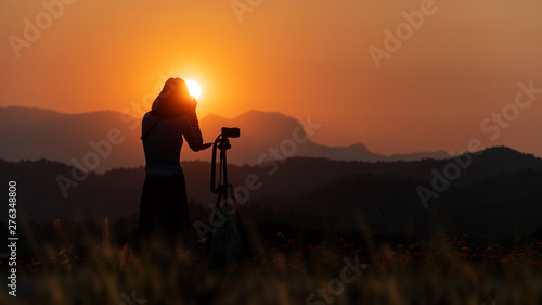 silhouette of photographer in sunset with mountain background 