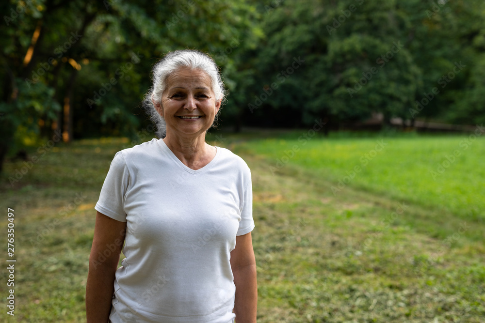 Beautiful senior woman is walking in the park Beautiful senior woman is walking in the park