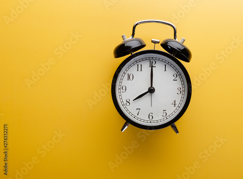 Alarm clock on yellow background top view. Concept of time.
