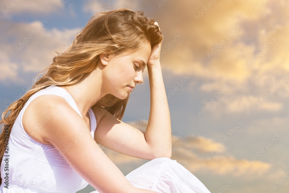 Sad pretty woman sitting holding head with hand on background