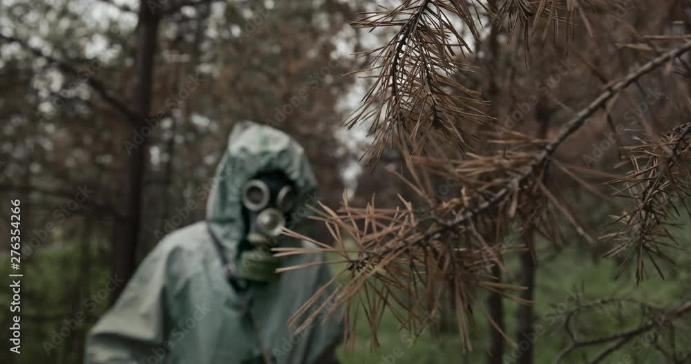 Person in WWII Hazmat suit and gas mask checking for contamination in a forest plantation with a counter and probe. Reconstruction of the events of the Chernobyl catastrophe on April 26, 1986 Person in WWII Hazmat suit and gas mask checking for contamination in a forest plantation with a counter and probe. Reconstruction of the events of the Chernobyl catastrophe on April 26, 1986