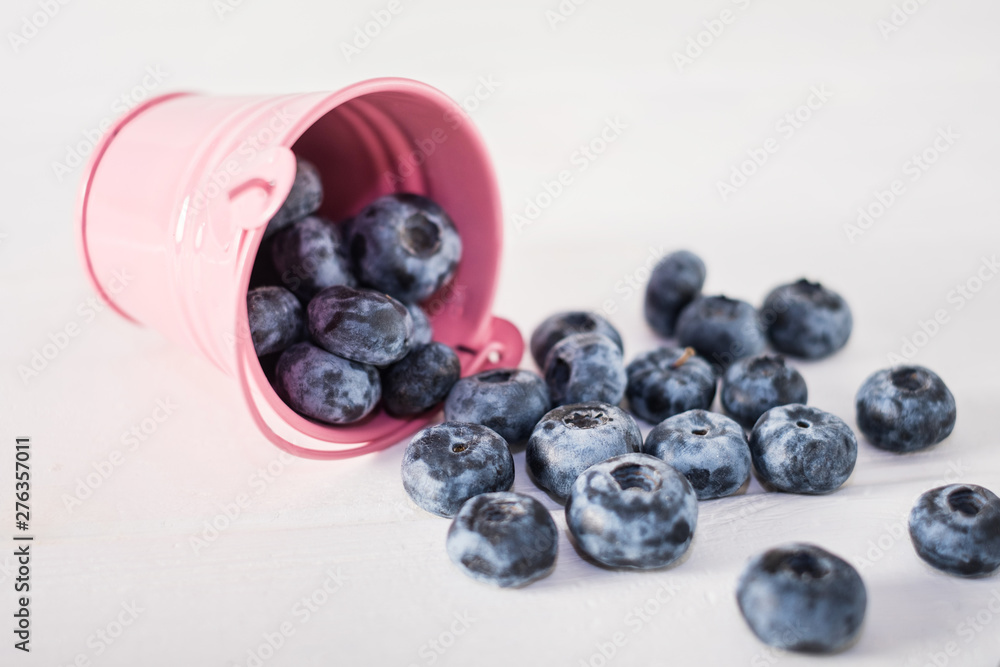Blueberries in pink bucket on white wooden table.Close up. Blueberries in pink bucket on white wooden table.Close up.