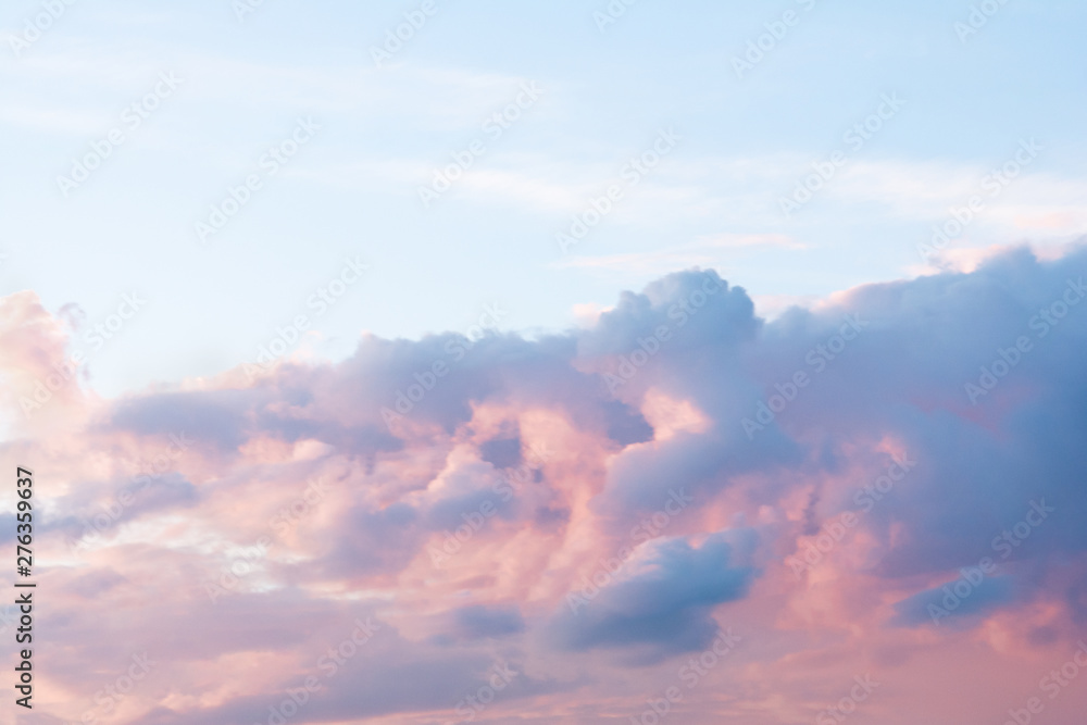 A dramatic cloud of blue, orange and pink on the blue sky in the form of a cat.