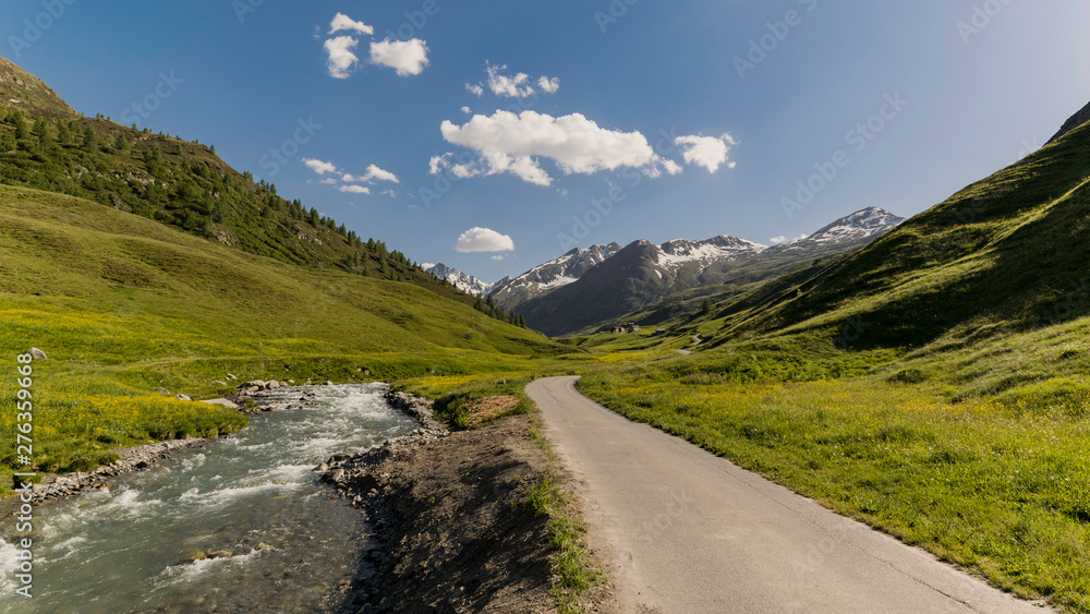 Road going through a valley in the mountains on a sunny day Road going through a valley in the mountains on a sunny day