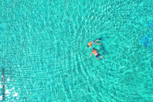 Father and son snorkels through tropical, turquoise waters, aerial view © Daniel CHETRONI
