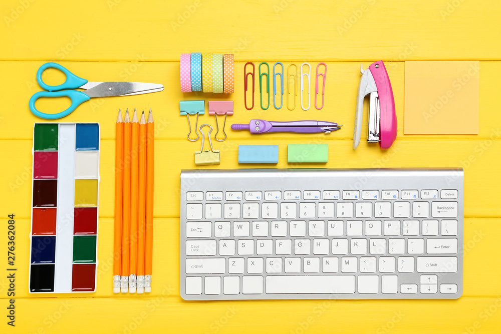 School supplies with keyboard on yellow wooden table