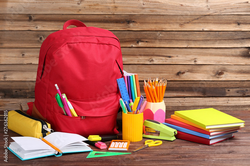 Backpack with school supplies on brown wooden table