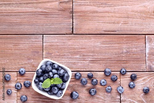 Ripe blueberries with green leafs on wooden table