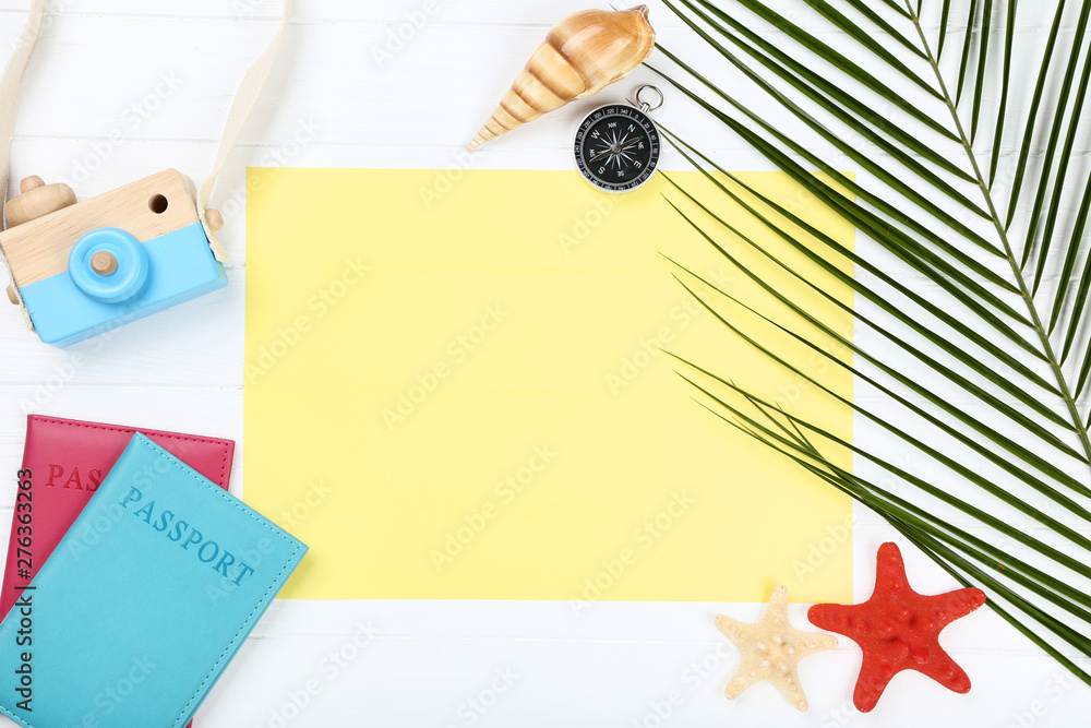 Blank sheet of paper with seashells, passport and palm leafs on white table Blank sheet of paper with seashells, passport and palm leafs on white table