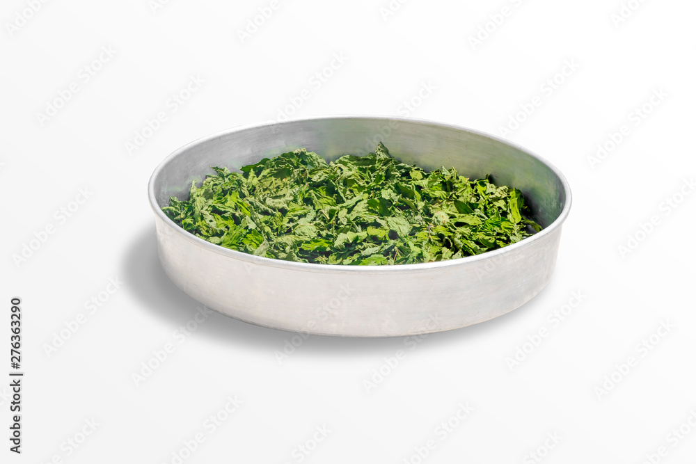 Dry healing mint leaves on a metal bowl isolated on white background. Seasoning Peppermint on a round tray. Dry healing mint leaves on a metal bowl isolated on white background. Seasoning Peppermint on a round tray.