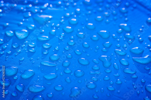 Large drops of water on a blue textile with a waterproof effect. Water-repellent impregnation. Texture drops on the fabric.
