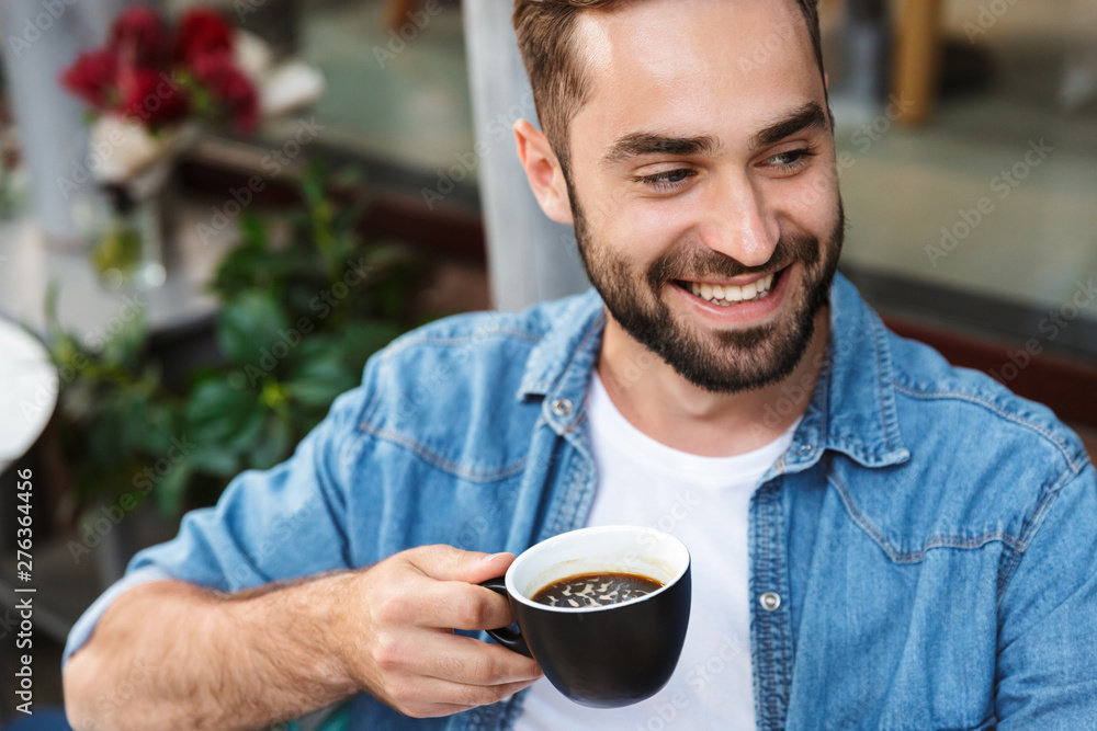 Handsome smiling man sitting at the cafe table Handsome smiling man sitting at the cafe table