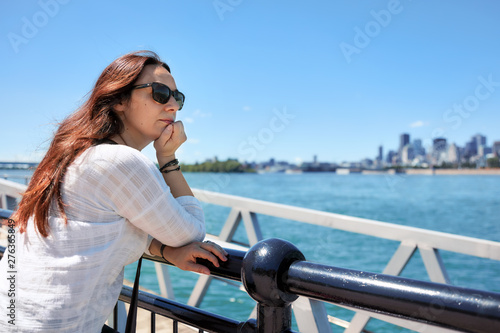 Redhead woman watching the scenery of Montreal city and the Saint Lawrence river on a sunny summer day in Quebec, Canada.