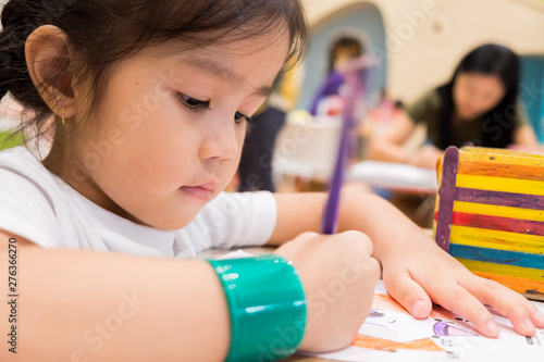 kids are painting picture with color pencil with their teacher in the classroom to learn paint skill. they are practicing the imagine lesson workshop. photo