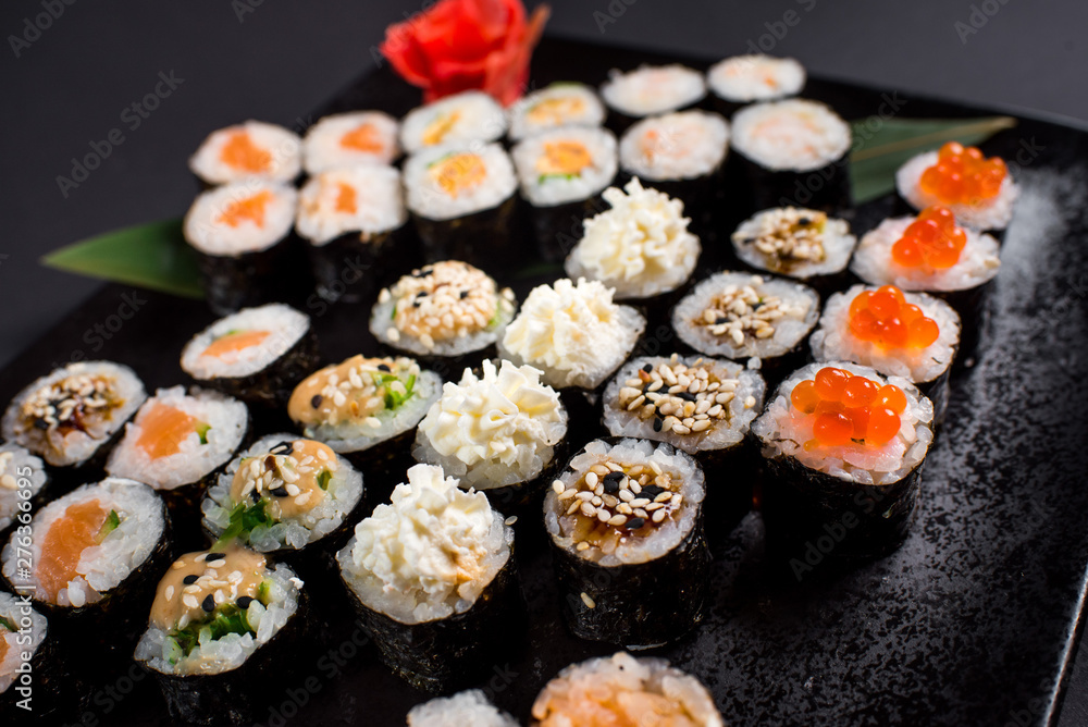 Japanese sushi rolls set served on black plate on dark background Japanese sushi rolls set served on black plate on dark background