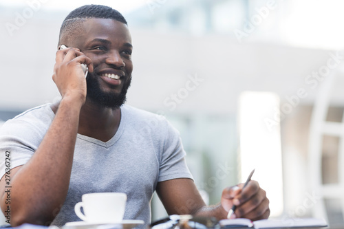 Portrait of african businessman talking by phone and drinking coffee