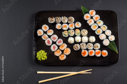 Japanese sushi rolls set served on black plate on dark background