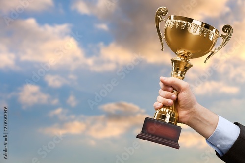 Hands holding golden trophy on background