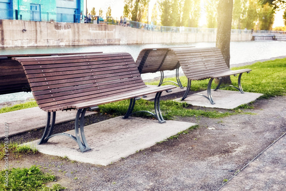 Wooden benches in a park near the riverside at sunset in summer Wooden benches in a park near the riverside at sunset in summer