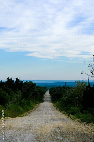 Long caliche rock road through scenic rural Texas landscape during summer. photo