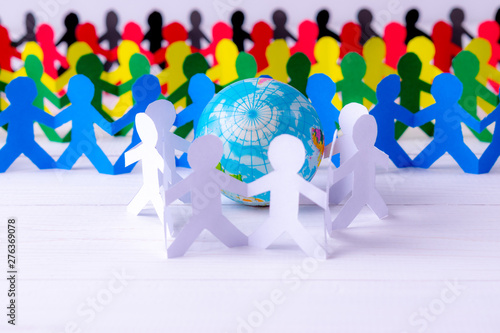 Circle of paper people holding hands around the globe made of paper cut . World Population Day.