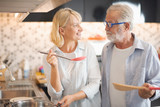 Closed up senior Caucasian couple are cooking and testing a meal or health food which smile and felling happy in kitchen at home. Old man looking old woman. Senior family activity at home concept.