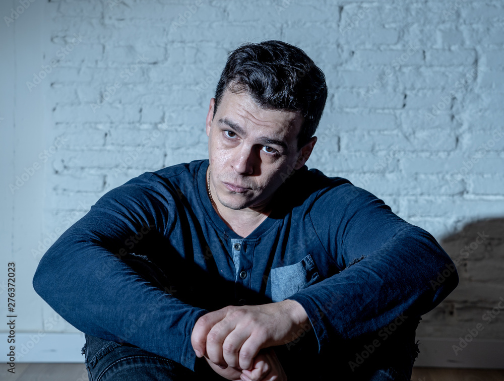 Desperate lonely unhappy caucasian man suffering from depression sitting alone on floor at home Desperate lonely unhappy caucasian man suffering from depression sitting alone on floor at home