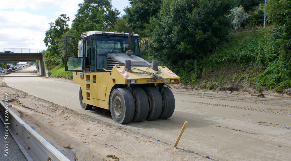 Road renewal, work on the closed highway lane. Preparation work for asphalting with a heavy vibratory roller compactor