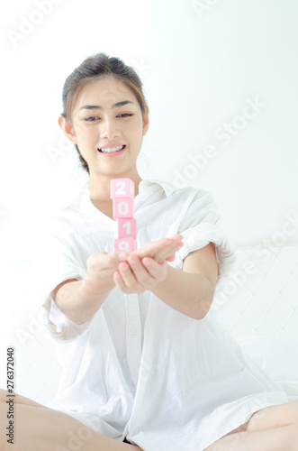 Small pink square wooden box with numbers in Asian women hands.Do not focus on the main object of this image.