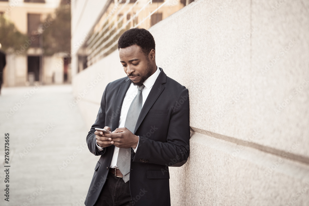 Young handsome businessman using mobile phone app sending message outside office in urban city Young handsome businessman using mobile phone app sending message outside office in urban city