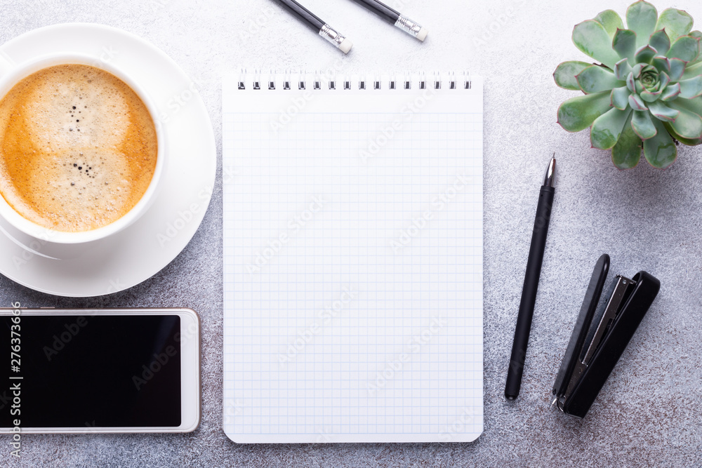 Office workplace with note pad, cup of coffee, smartphone and stationery on gray stone background Top view Copy space Office workplace with note pad, cup of coffee, smartphone and stationery on gray stone background Top view Copy space